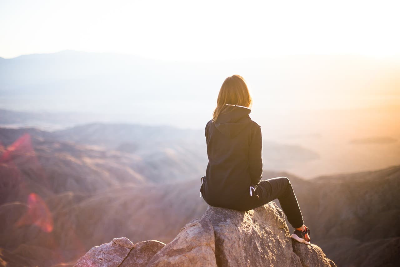 A person looking out over a valley at sunrise