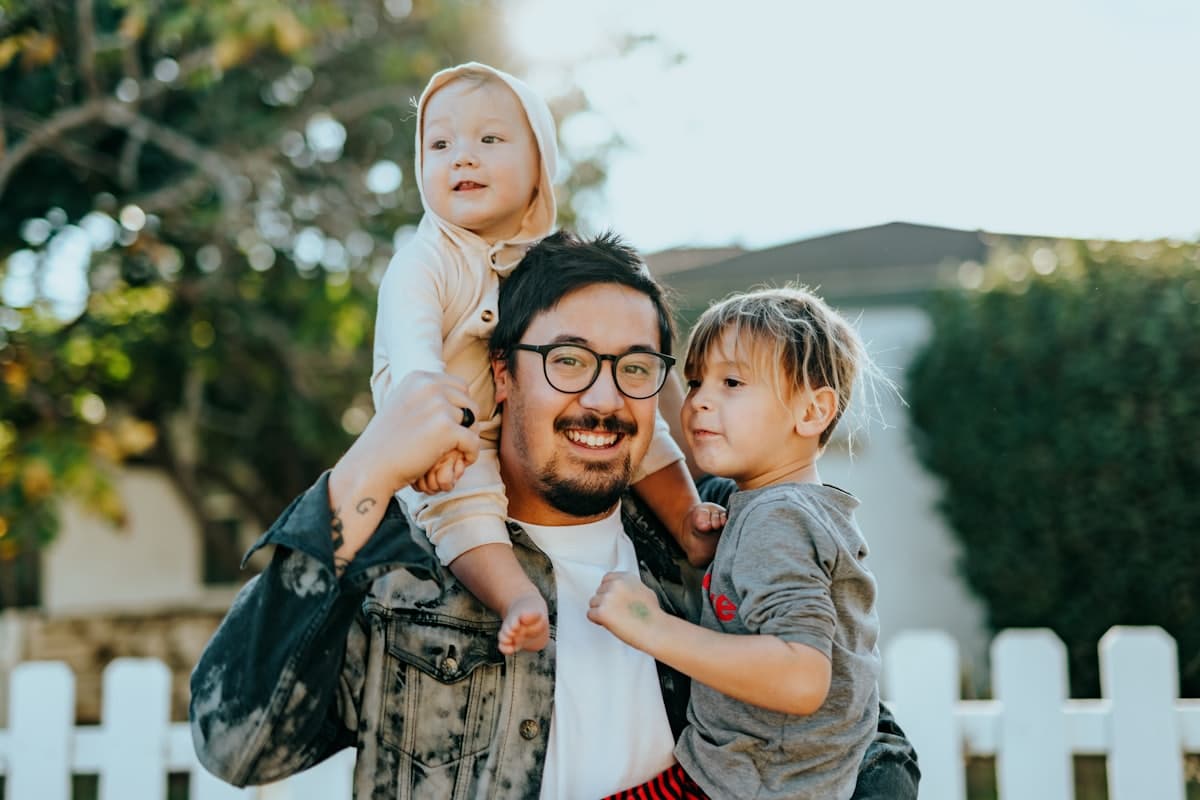 A father laughing while carrying his two young children